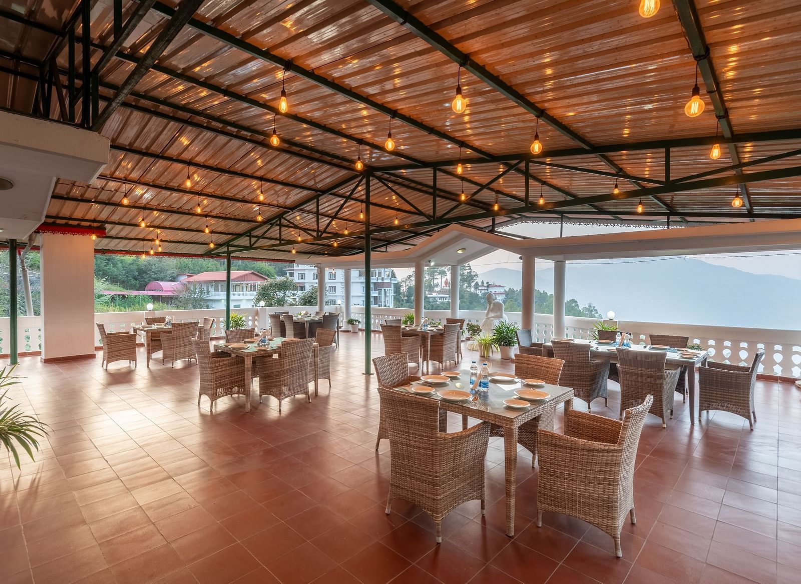 Covered terrace at DLS Tehri Club Resort with tables and chairs, perfect for enjoying the views.